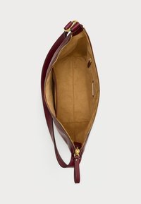 Bordo kožni ranac s zlatnim zatvaračem, s prostranim bež interijerom i jednim remenom za nošenje preko ramena.