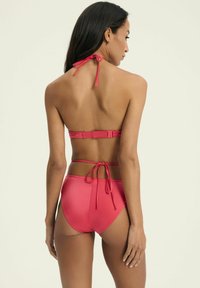 Czerwony zestaw bikini z halterem i regulowanymi ramiączkami, gładka tkanina, wysoki stan dolnej części oraz minimalistyczny design bez wzorów.