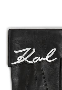 Zwarte leren handschoen met een opgevouwen manchet en een zilverkleurig metalen accent met de tekst "Karl." Gestructureerde afwerking met zichtbare stiksels.