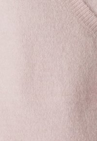 Pullover lavorato a maglia rosa chiaro mostrato da vicino, caratterizzato da una texture morbida, colletto a coste e un design semplice e senza cuciture.