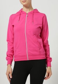 Vaaleanpunainen vetoketjullinen huppari pehmeästä kankaasta, jossa on huppu, etutaskut sekä resorit hihoissa ja helmassa. Vetoketju ja kiristysnauhat hopeanväriset.