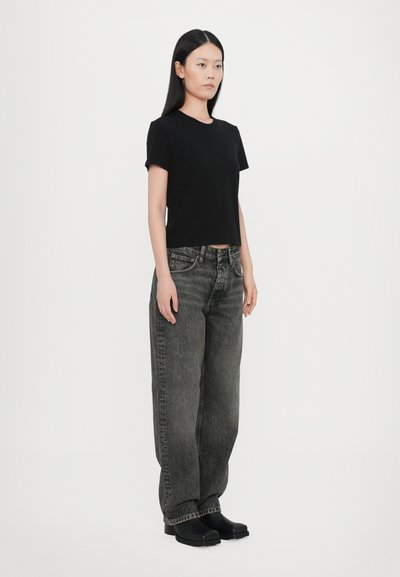 Black short-sleeve crop top paired with loose-fitting gray jeans and black shoes. The outfit features a simple and clean design.