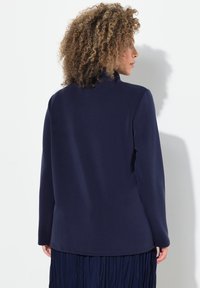 Marinblå sweatshirt med hög krage och långa ärmar, med en mjuk textur och en förlängd baktill.