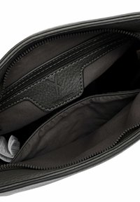 Interno di una borsa a tracolla nera in pelle, con molteplici scomparti con zip e fodera in tessuto, dotato di una patch con logo cucita all'interno.
