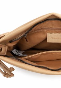 Wnętrze beżowej skórzanej torebki, wyposażone w przegrodę na zamek błyskawiczny oraz gładką, teksturowaną podszewkę. Zawiera dodatkową kieszeń do przechowywania.