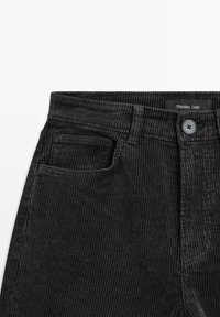 Černé kordové kalhoty s vertikálním vroubkovaným vzorem, přední kapsou a zapínáním na knoflík s visačkou "Massimo Dutti."