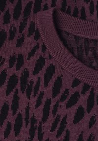Gros plan d'un pull en maille violet avec un motif léopard noir et un col rond côtelé.
