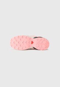 Trail running shoe outsole in pink rubber, featuring a textured, patterned surface with multi-directional lugs for traction and stability.