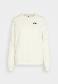 Vit långärmad Nike-tröja med rundad halsringning och svart Nike-logotyp på vänster bröst mot en enhetlig bakgrund.
