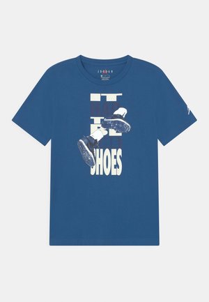 Blauwe katoenen t-shirt met een grafische print van schoenen en tekst die zegt "HET MOEST DE SCHOENEN ZIJN." Korte mouwen, ronde hals.