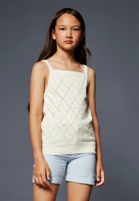Top senza maniche lavorato a maglia in crema chiara con motivo a rombi e ricamo floreale. Abbinato a pantaloni corti a scacchi blu chiaro.