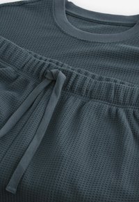 Dunkelgrauer, strukturierter Sweatshirt mit rundem Ausschnitt und elastischem Bund. Verfügt über eine Kordelzugschnur für eine individuelle Anpassung.