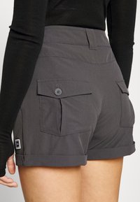 Gray shorts made of textured fabric with rolled cuffs, featuring two back pockets with button closures and a small brand label on the side.