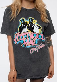 Gray oversized t-shirt featuring a colorful graphic of two penguins in top hats and "Fleetwood Mac On Tour" text in pink and blue.