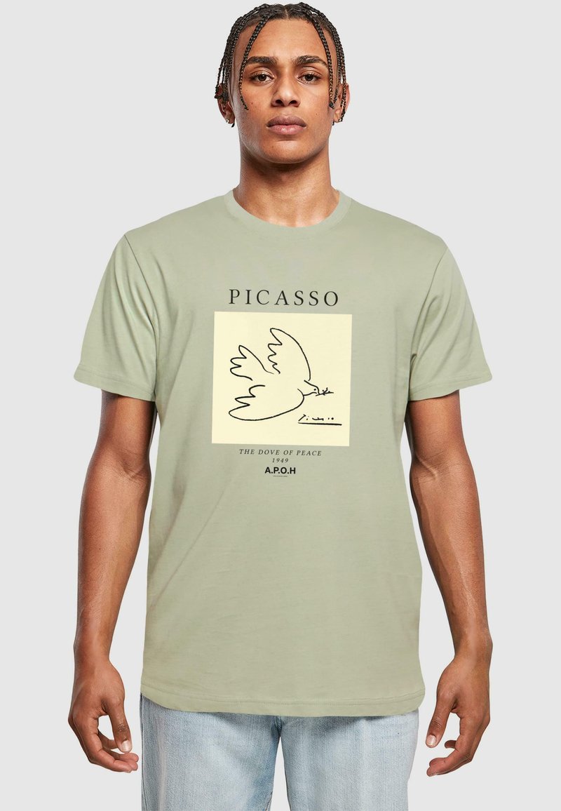 Lys grøn t-shirt med et Picasso-design af en due, med sorte konturer og typografi, der siger "PICASSO" og "FREDENS DUE 1949."