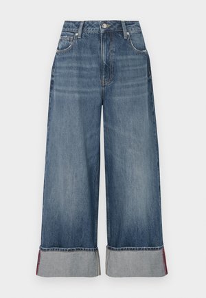 Viddebukser i denim med en mellomblå vask, presentert med høy midje, fem lommer, kontrastsøm og oppbrettede ermer med røde detaljer.