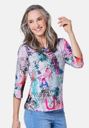 Multikleurige lange mouw shirt met bloemen- en tekstpatronen. Gemaakt van zachte stof, met een ronde halslijn en levendige roze, blauwe en zwarte accenten.