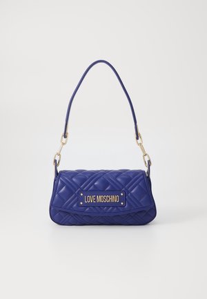 Borsa a tracolla viola trapuntata con un manico superiore singolo, hardware dorato e una targhetta con il logo prominente sul davanti. Superficie lucida e texturizzata.