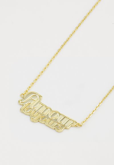 Guld halskæde med en kæde og et vedhæng, der står "Amour Toujours" i en stiliseret, udskåret skrifttype. Glat, reflekterende overflade.