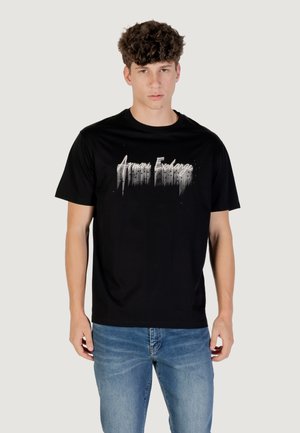 T-shirt en coton noir avec le logo "Armani Exchange" dans un design dégradé. Encolure ronde simple, manches courtes et coupe décontractée. Associé à un jean bleu.