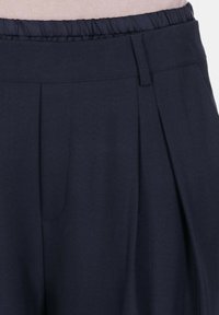 Pantaloni plissettati blu scuro con vita elasticizzata, realizzati in un tessuto testurizzato, caratterizzati da cuciture pulite e senza hardware o motivi visibili.