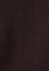 Tissu tricoté marron foncé avec un motif de points serré et uniforme créant une surface texturée lisse.