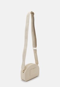 Beżowa torebka crossbody o gładkim, zaokrąglonym kształcie. Posiada zamek błyskawiczny, przednią kieszeń oraz teksturowany pasek z detalem logo.