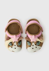 Brown and white plastic clogs featuring a cow design, with pink accents and a star-shaped decoration. Textured footbed for grip.