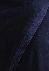 Tengerészkék bársony anyag, sima felülettel és enyhe fényességgel, az él mentén varrásrészlettel. A dizájn letisztult és modern.