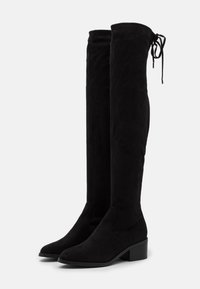 Botas de ante negras por encima de la rodilla con tacones bajos en bloque y detalle de cordones en la parte trasera del borde superior.
