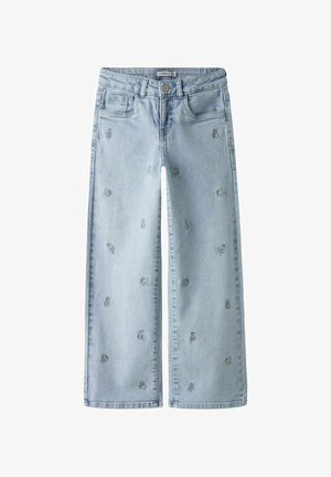 Svijetloplave traperice širokih nogavica, izrađene od trapera, s malim cvjetnim vezom. Klasični dizajn s pet džepova i kopčanjem na gumbe te ravnim rubom.