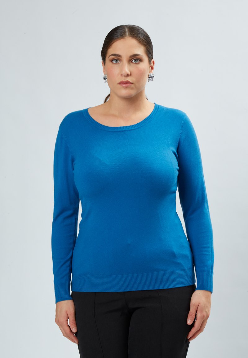 Langsleeve, ronde hals trui in felle blauwe kleur, gemaakt van zachte stof met een geribbelde onderkant en manchetten, gecombineerd met zwarte broek.