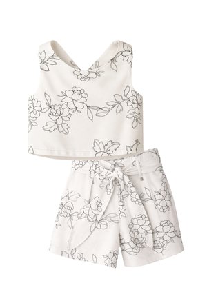 Completo bianco in due pezzi con motivi floreali neri a linee, composto da un top corto senza maniche con scollo a V e pantaloncini a vita alta con fiocco in tessuto.