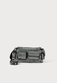 Schwarze Handtasche, verziert mit silbernen runden Nieten, in rechteckiger Form, mit einer vorderen Reißverschlusstasche und verstellbarem Tragegurt. Logo sichtbar.