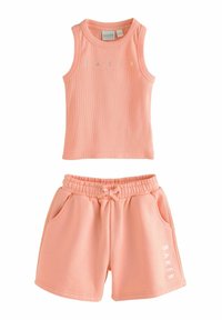 Linnen i persikofärg med shorts, tillverkat av mjukt material, med ribbat mönster och tryck på framsidan. Shortsen har ett elastiskt midjeband och fickor.