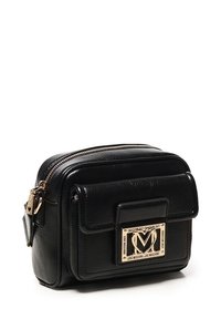 Borsa a tracolla compatta in pelle nera con tasca frontale con patta, piastrella del logo a forma di cuore dorato e chiusura superiore a zip.