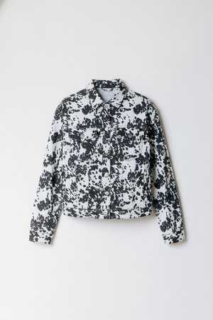 Czarna i biała kurtka dżinsowa w cętki, z długimi rękawami, spiczastym kołnierzem, dwoma kieszeniami na piersi, zapięciem na guziki z przodu oraz krótkim krojem.