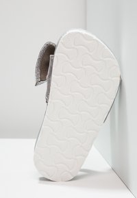 Szare buty z materiału z fakturowaną białą gumową podeszwą, z okrągłym wzorem i wyściełanymi krawędziami dla komfortu i stabilności.