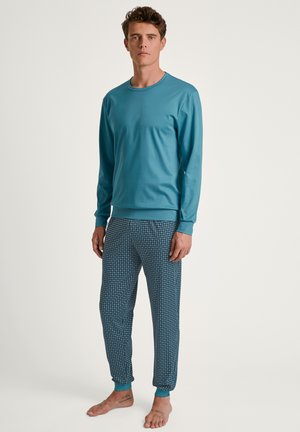 Langarmige blauwe top in combinatie met patroonblauwe pyjamabroeken. De top heeft een ronde halslijn; de broeken hebben elastische boorden en een geometrisch ontwerp.