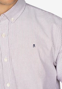 Wit overhemd met dunne rode strepen, voorzien van een kraag en een klein marineblauw geborduurd logo op de linkerkant van de borst. Geweven stof.