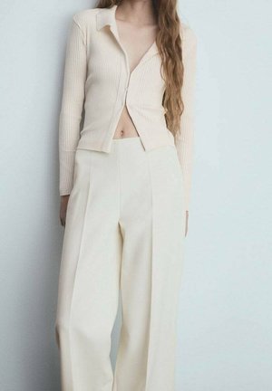 Geribbelde, lichtbeige cropped cardigan met een kraag en knopen aan de voorkant, gecombineerd met een brede, geplooide roomkleurige broek. Over het algemeen een gladde textuur.