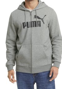 Felpa grigia con zip in un tessuto morbido, caratterizzata da un grande logo nero "PUMA" sul davanti, con cordini e tasche frontali.