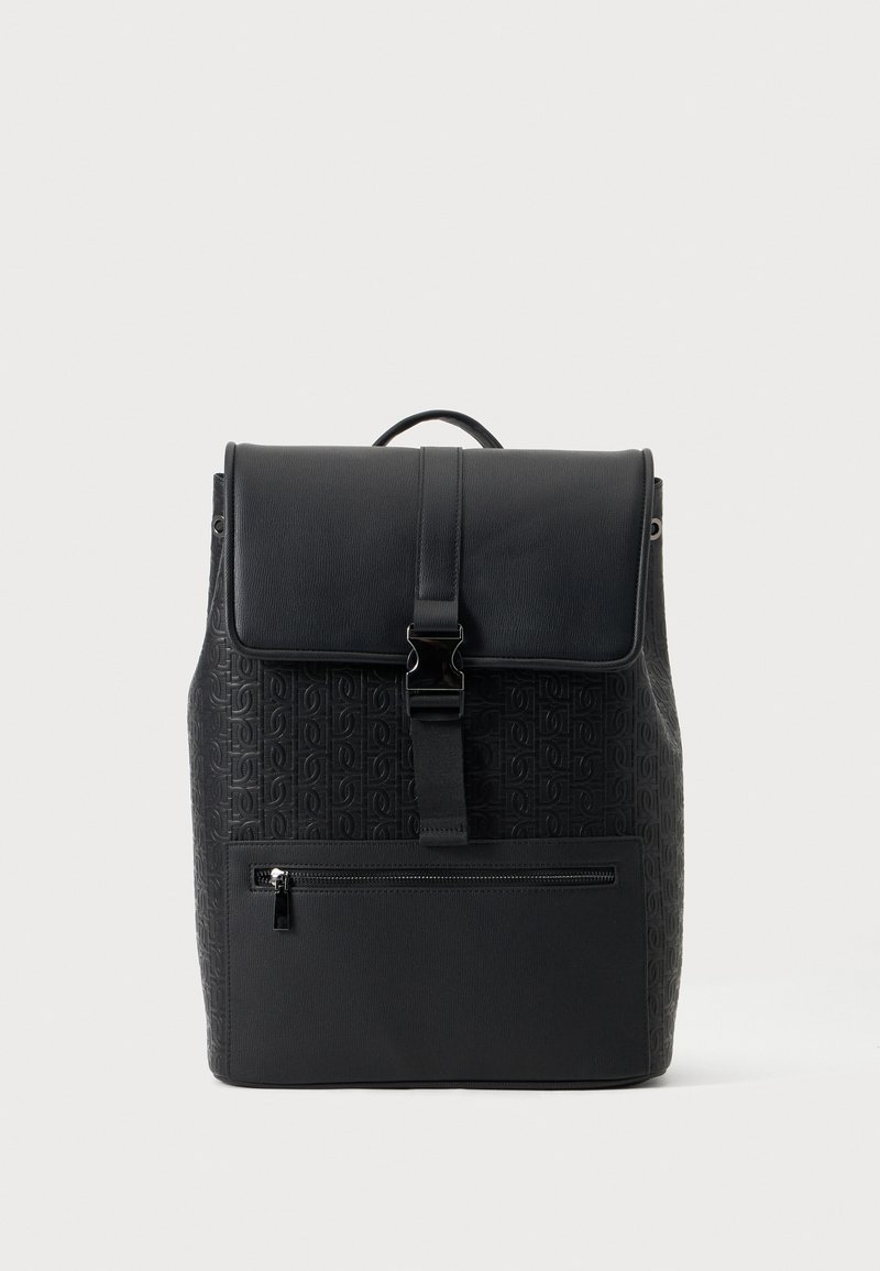 Sac à dos noir texturé avec rabat supérieur et fermeture par boucle, poche avant zippée et poignée de transport sur un fond clair uni.