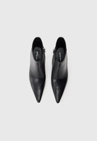 Pair of black pointed-toe leather ankle boots with side zippers and visible Michael Kors branding inside.