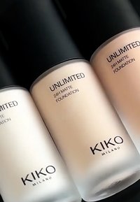 Tre flasker av KIKO Milano Unlimited 24H Matte Foundation, variert i nyanser fra hvit til lys beige, med svarte lokk og minimalistiske etiketter.