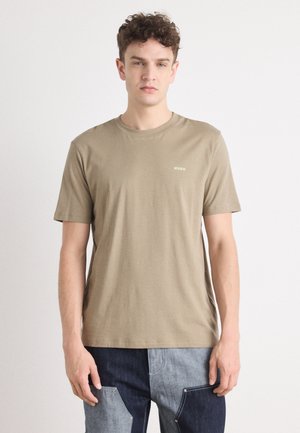 T-shirt à manches courtes couleur kaki en coton, avec un col rond et un petit logo "HUGO" vert sur la poitrine gauche. Texture douce.