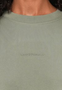 Olijfgroene geribde sweatshirt met een ronde halslijn en subtiele textuur; voorzien van een witte reliëf "Marc O'Polo DENIM" logo.
