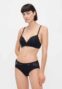 Black lingerie set featuring a plunge bra with thin straps and a matching brief with lace accents on the waistband. Smooth texture.