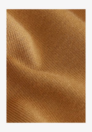 Ruskea neuloskangas, jossa on pehmeä rakenne, ribattuja kuvioita ja hienovaraisia sävyvaihteluita, korostaen sen yksityiskohtaista käsityötä.
