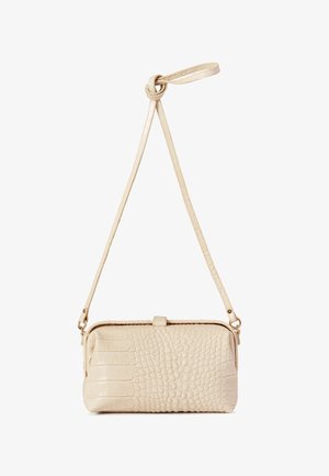 Petit sac bandoulière beige avec texture embossée façon crocodile et une longue sangle ajustable nouée en haut.